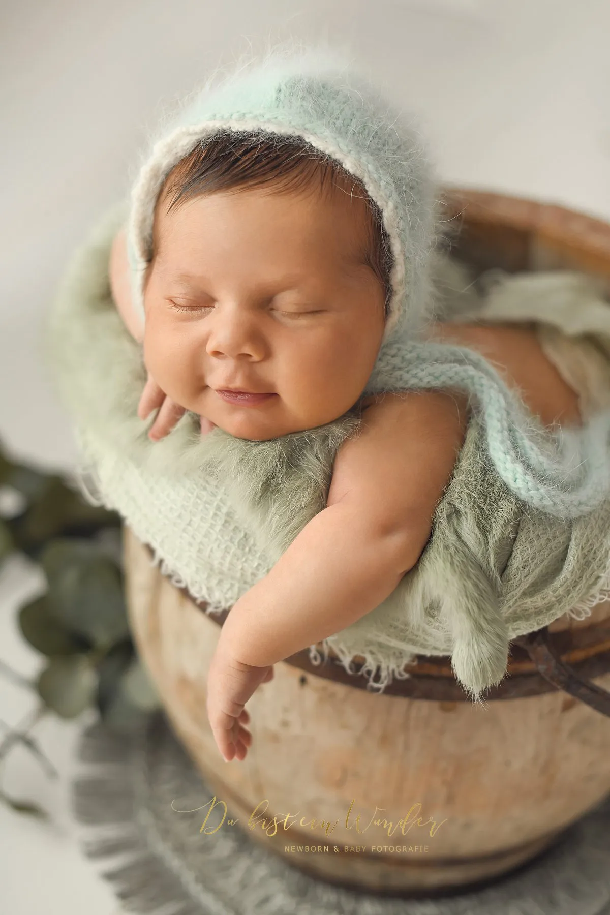 Friedlich schlafendes Neugeborenes in grauem Körbchen beim Newborn Shooting